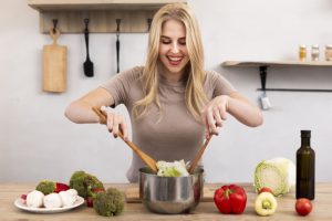 happy woman mixing bowl with salad